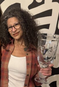 Photo of Annette May, holding the 2025 Michigan Beer Champion Award