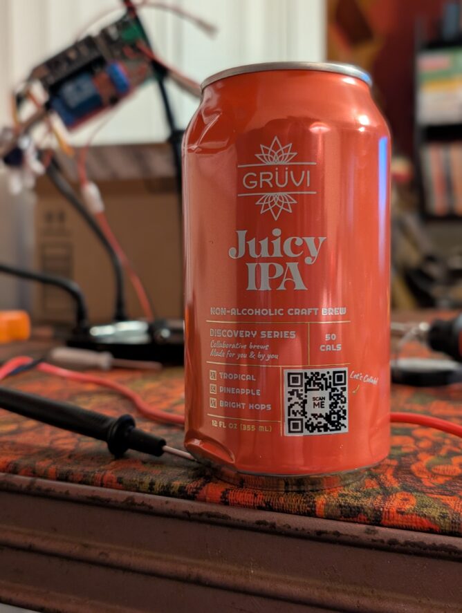 A can of GRÜVI Juicy IPA sitting on a table in front of an electrical workbench.